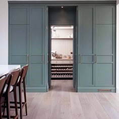 an open door to a kitchen with blue cabinets and stools on the floor in front of it