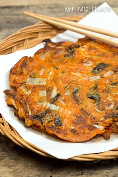 an omelet is sitting in a basket with chopsticks next to it