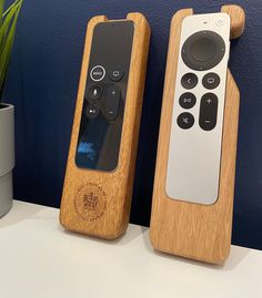 two wooden remote controls sitting on top of a table next to a potted plant