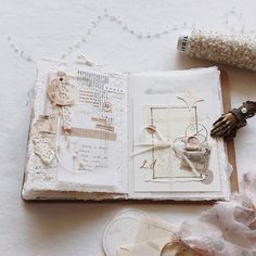 an open book on a table next to some flowers and other things that are laying around