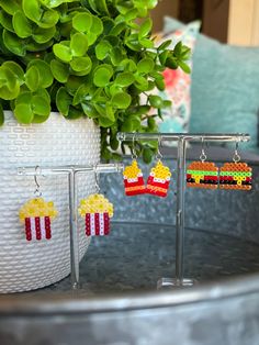 the earrings are made out of legos and have popcorn in them on display next to a potted plant