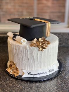 a graduation cake decorated with gold flowers and a black cap on top that says congratulations julia