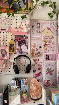 a desk with headphones on top of it next to a wall covered in pictures