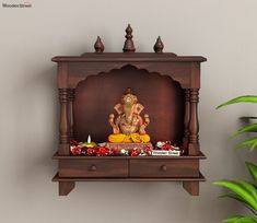 there is a small wooden shelf with an elephant statue on it and flowers in the corner