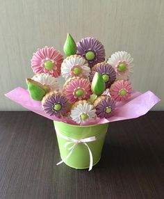 a green bucket filled with cookies covered in icing and flowers on top of a table