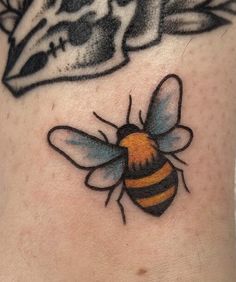 a close up of a tattoo on the side of a person's stomach with a bee