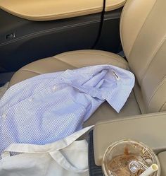 a blue shirt is sitting in the back seat of a car next to a cup