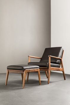 a chair and footstool sitting in an empty room