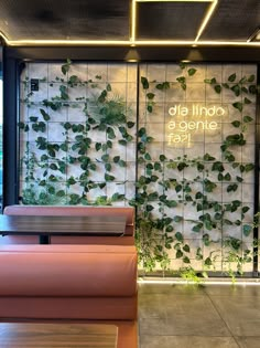 the interior of a restaurant with plants growing on the wall and tables in front of it