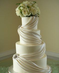 a three tiered white wedding cake with flowers on top