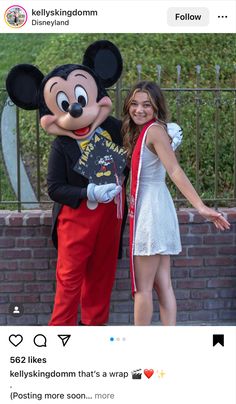 two people standing next to each other in front of a mickey mouse costume and posing for the camera