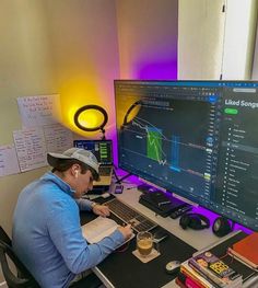 a man sitting in front of a computer on top of a desk with headphones