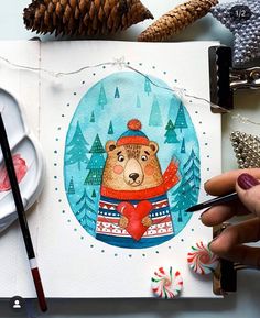 a hand is holding a pen and drawing a bear in a sweater with candy canes