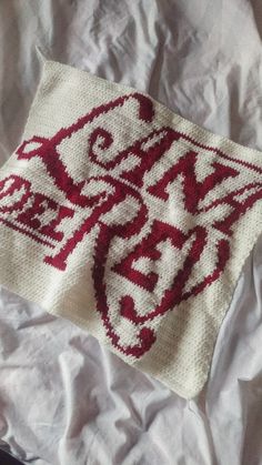 an embroidered piece of cloth on top of a white sheet with the word love written in red