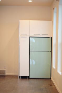 an empty room with a refrigerator and cabinets