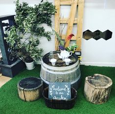 there is a wooden barrel on the grass next to two planters and a sign that says welcome to our garden