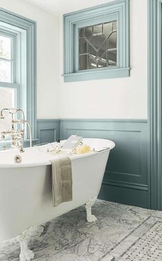 an old fashioned bathtub in a bathroom with blue trimmings and green windows