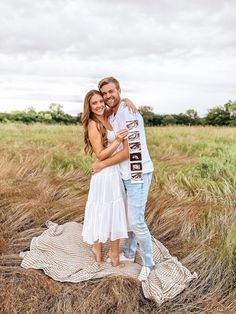 a man and woman hugging in the middle of a field