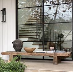 a wooden bench sitting in front of a window next to a stair case and potted plant