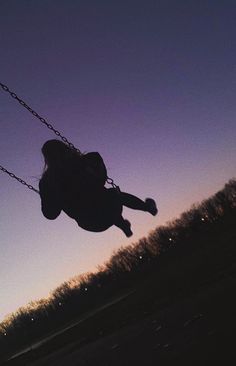 a person is swinging on a swing at sunset