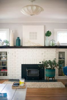 a living room filled with furniture and a fire place in front of a white brick fireplace