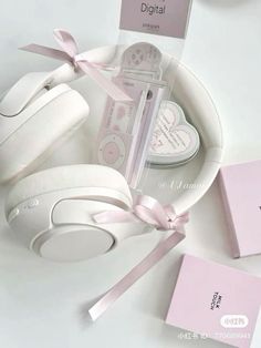 the white headphones are on display with pink tags and ribbons around them, along with other items