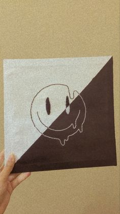 a person holding up a piece of paper with a drawing on it that looks like a smiley face