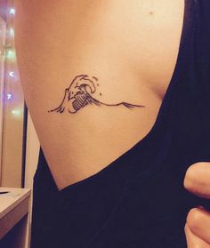 a woman's arm with a tattoo on it that has a wave coming out of the ocean