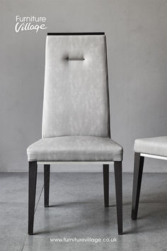 a pair of white chairs sitting next to each other in front of a gray wall