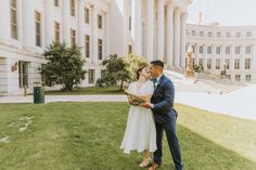 a man and woman standing in front of a large building with columns on each side