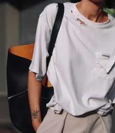 a person with a white shirt and tan pants holding a black bag in their hand