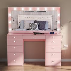 a pink vanity desk with lights on it