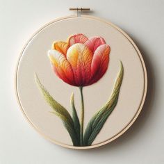 a painting of a flower on a white wall hanging from a wooden hoop with two green leaves