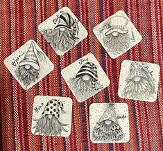 four coasters with different designs on them sitting on a red and white table cloth