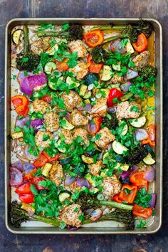 a pan filled with vegetables and meat on top of a wooden table