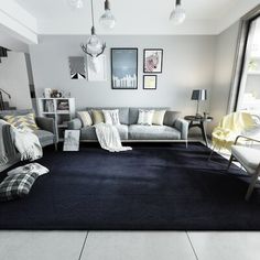 a living room filled with furniture next to a large window and a rug on the floor