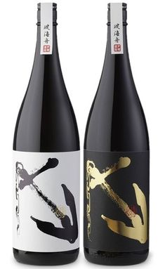 two bottles of wine sitting next to each other on a white surface with gold lettering