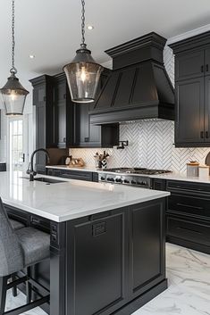 a kitchen with black cabinets and white marble counter tops, two pendant lights hanging from the ceiling