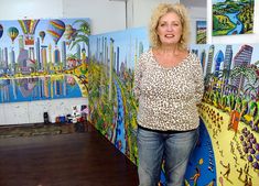 a woman standing in front of some paintings