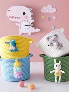 three baskets with stuffed animals in them on a table next to a clock and wall