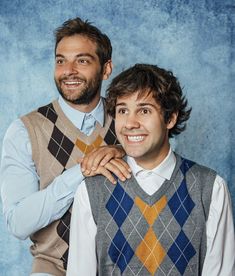 two men in sweater vests and ties posing for a photo with their arms around each other