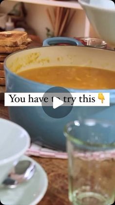 a bowl of soup sitting on top of a wooden table next to plates and bowls