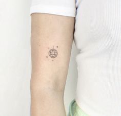 a woman's arm with a small globe tattoo on the left side of her arm