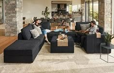 two people sitting on couches in a living room with stone walls and wood flooring