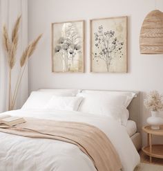 two paintings on the wall above a bed in a room with white sheets and pillows