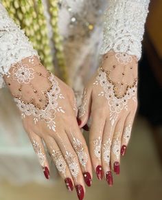 a woman with red nails and white lace on her hands