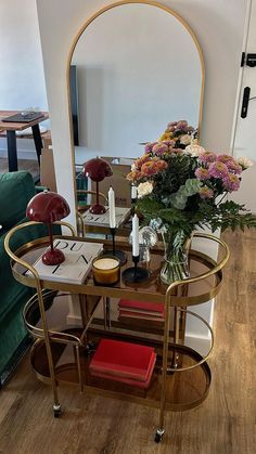 a table with flowers and candles on it in front of a mirror