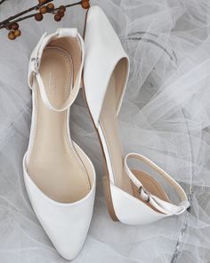 a pair of white high heeled shoes sitting on top of a bed