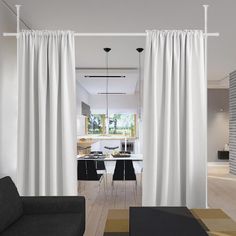 an open living room and dining area with white curtains hanging from the ceiling, along with black chairs