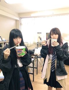 two young women are eating food in a classroom